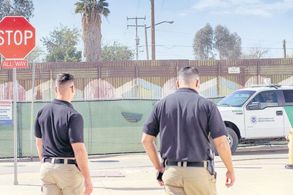 Agentes en Calexico, California, patrullan cerca de una reja que marca el límite con México.