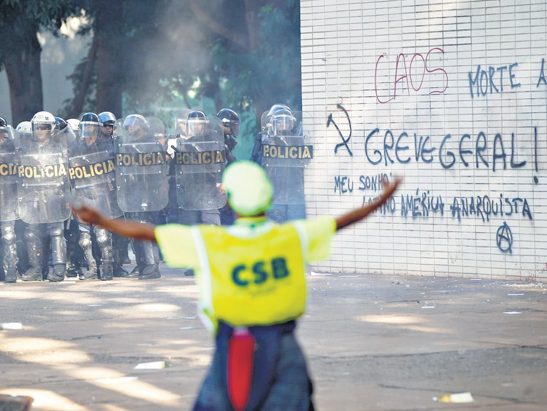 Manifestantes con los brazos en alto enfrentan a la policía antimotines en Brasilia.