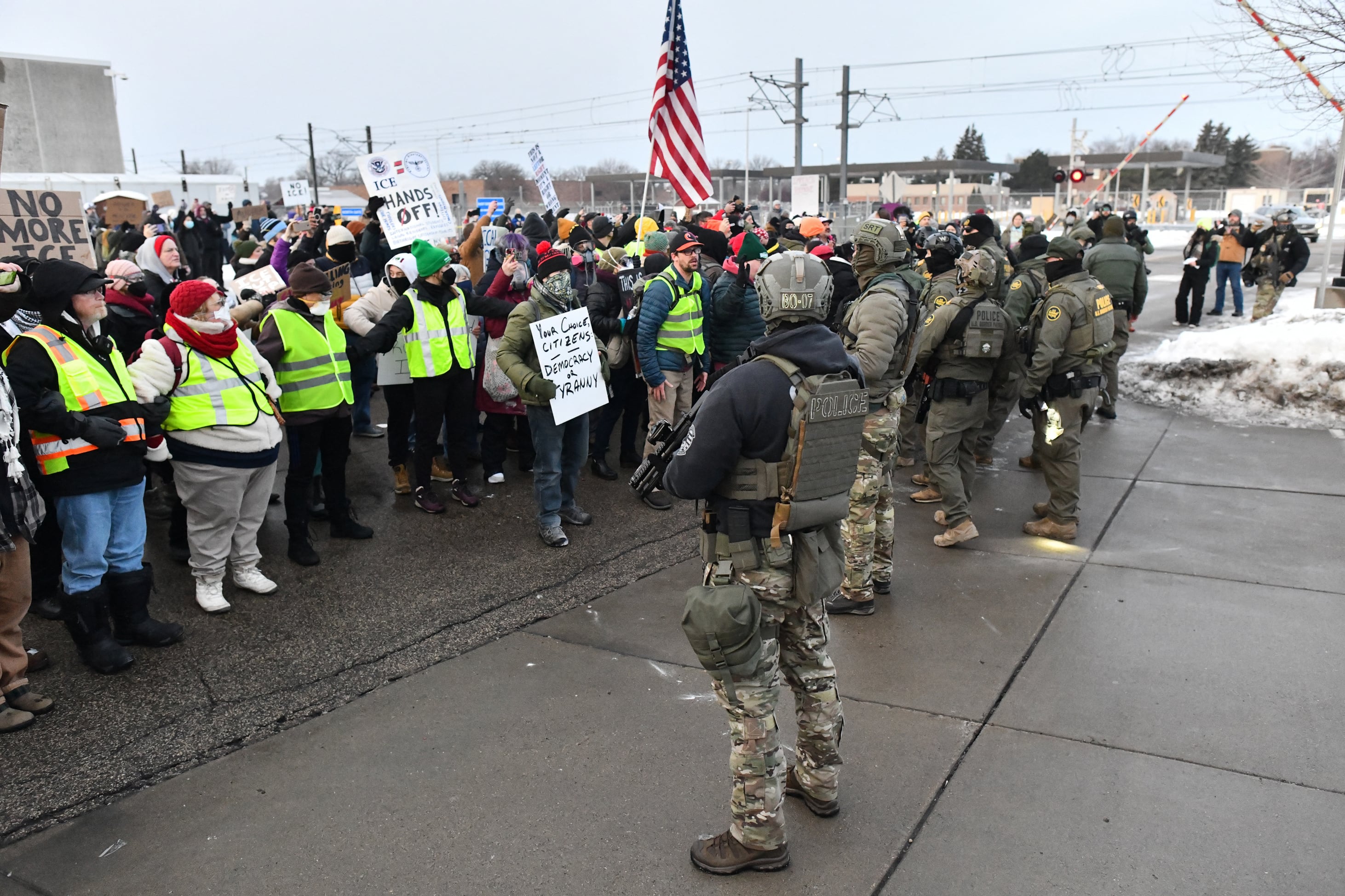 Federal agents stand watch as protestors gather outside the Bishop Henry Whipple Federal Building in Saint Paul, Minnesota, on January 8, 2026. A US Immigration and Customs Enforcement (ICE) agent shot and killed an American woman on the streets of Minneapolis January 7, leading to huge protests and outrage from local leaders who rejected White House claims she was a domestic terrorist. The woman, identified in local media as 37-year-old Renee Nicole Good, was hit at point blank range as she apparently tried to drive away from agents who were crowding around her car, which they said was blocking their way. (Photo by Octavio JONES / AFP)