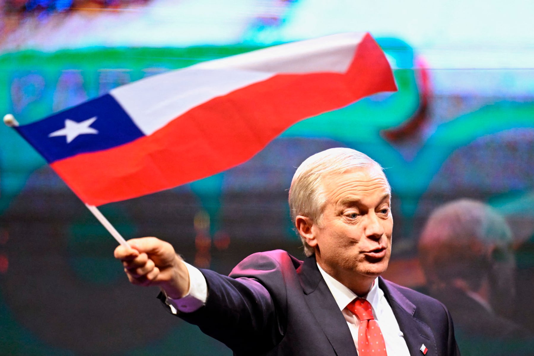Chile's presidential candidate Jose Antonio Kast, of the Partido Republicano party, waves a Chilean flag after the first exit poll results of the general election in Santiago on November 16, 2025. Leftist former labor minister Jeannette Jara and far-right leader Jose Antonio Kast were leading the country's presidential race on November 16, 2025, according to partial results, which show them heading to a December run-off. (Photo by Marvin RECINOS / AFP)