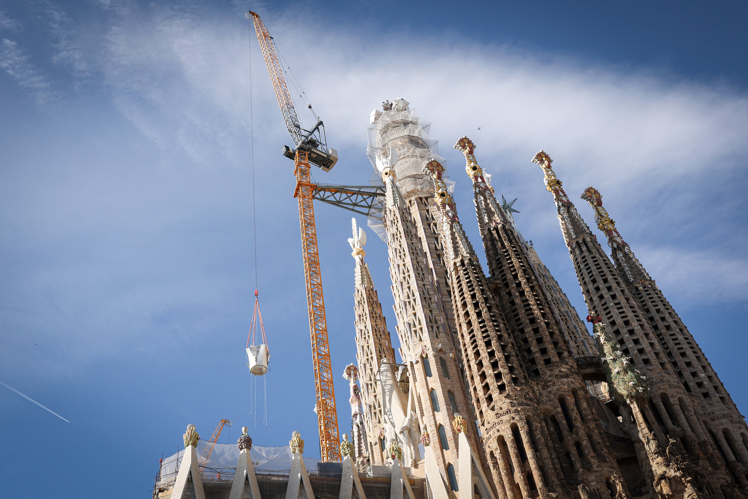 A crane lifts the final piece of the 17 meters high and 13.5 meters wide cross that completes the Sagrada Familia's Tower of Jesus Christ in Barcelona