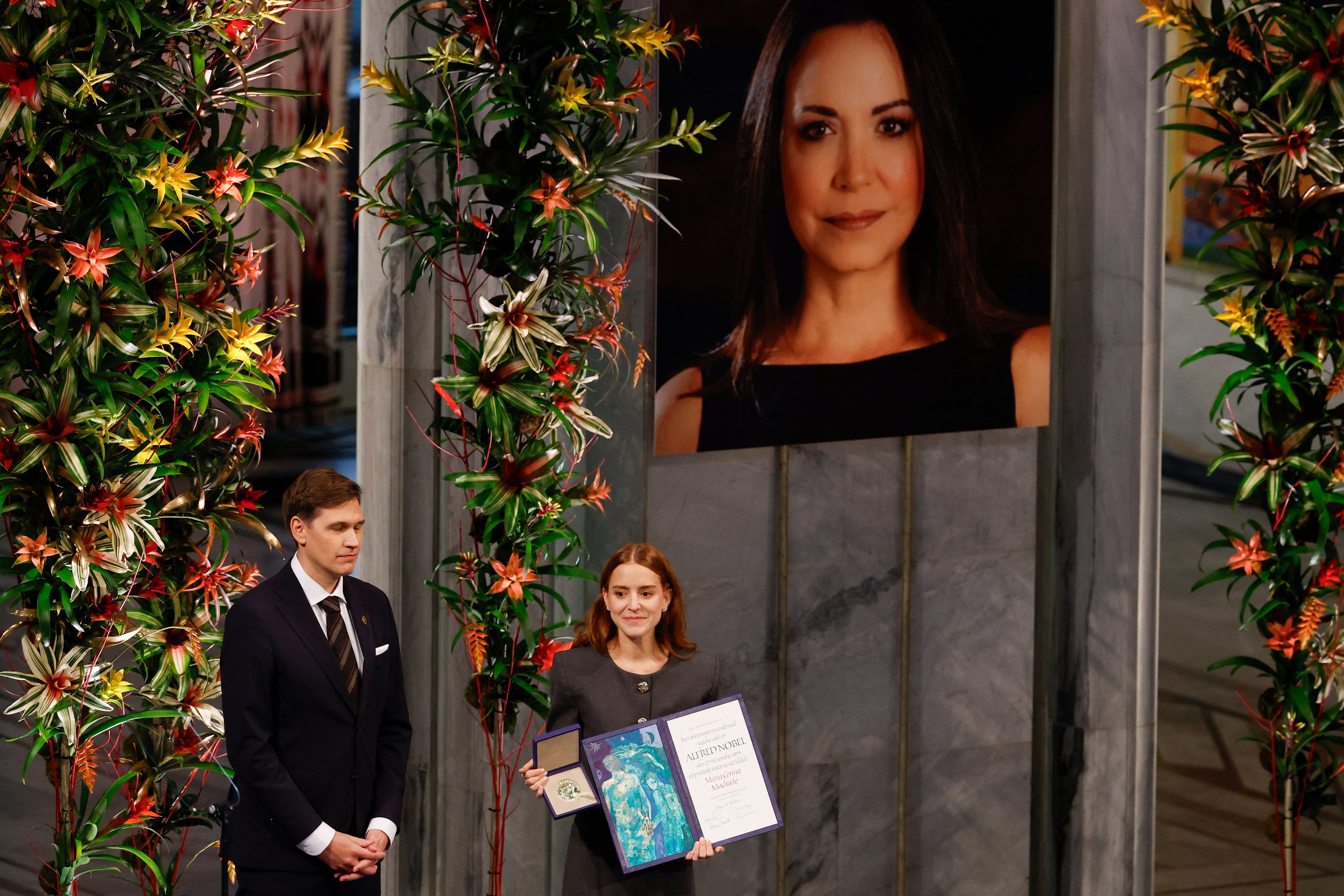 Ana Corina Sosa (R), daughter of Venezuelan opposition leader Maria Corina Machado, receives the Nobel Peace Prize for her mother from the Chair of the Norwegian Nobel Committee Jorgen Watne Frydnes (L) at the Nobel Peace Prize ceremony at Oslo City Hall on December 10, 2025 in Oslo, Norway. The 2025 Nobel Peace Prize was awarded to Machado for her efforts to bring democracy to Venezuela, challenging the iron-fisted rule of Venezuelan President Nicolas Maduro, who has been president since 2013. (Photo by Odd ANDERSEN / AFP)
