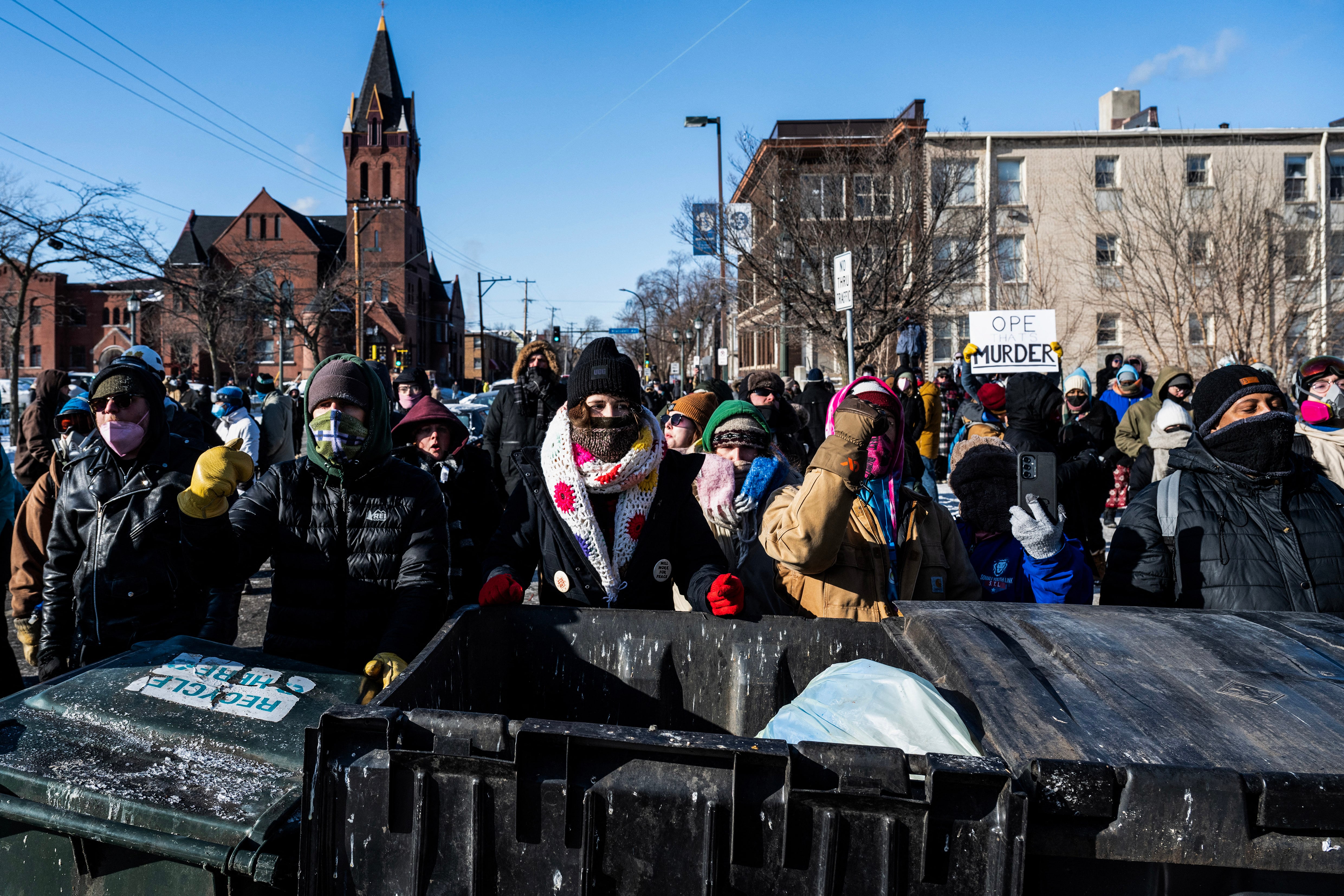 Demonstrators stand behind a barricade of trash bins as they gather near the site of where state and local authorities say a man was shot and killed by federal agents earlier in the morning in Minneapolis, Minnesota, on January 24, 2026. Federal immigration agents shot dead a man in Minneapolis on Saturday, officials said -- the second fatal shooting of a civilian in the city, sparking fresh protests and outrage from state officials. The death came less than three weeks after US citizen Renee Good was shot and killed by an Immigration and Customs Enforcement officer involved in sweeps to round up undocumented migrants. (Photo by ROBERTO SCHMIDT / AFP)