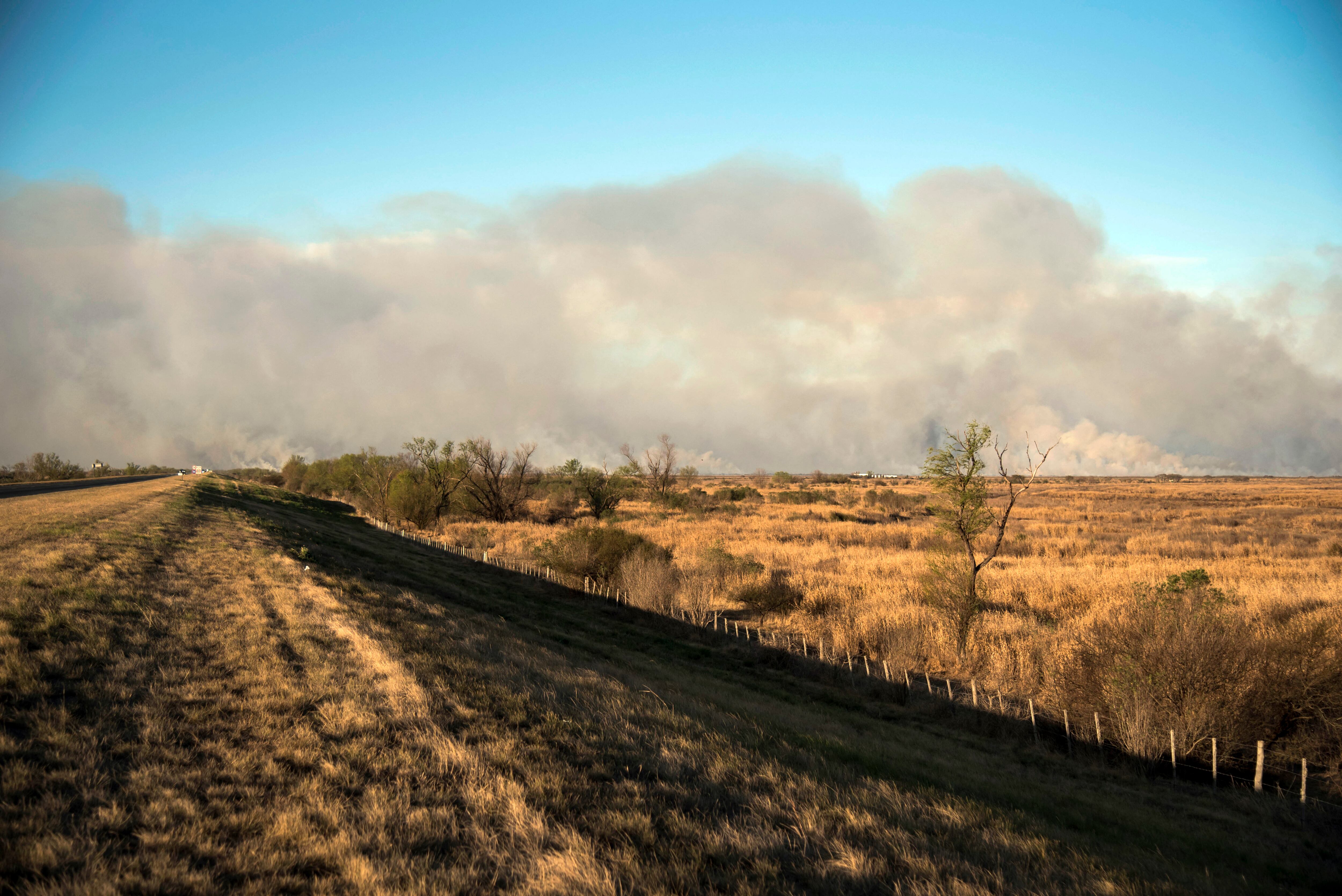 El humo ondea de los incendios forestales que atraviesan los humedales en las islas a lo largo del delta del Paraná cerca de Victoria, en la provincia argentina de Entre Ríos, frente a la ciudad de Rosario, en la provincia de Santa Fe, el 15 de agosto de 2022. - Personas en Rosario, al otro lado del río, que están siendo afectadas por el humo, se han manifestado contra la quema de campos para la limpieza de tierras. (Foto por AFP)