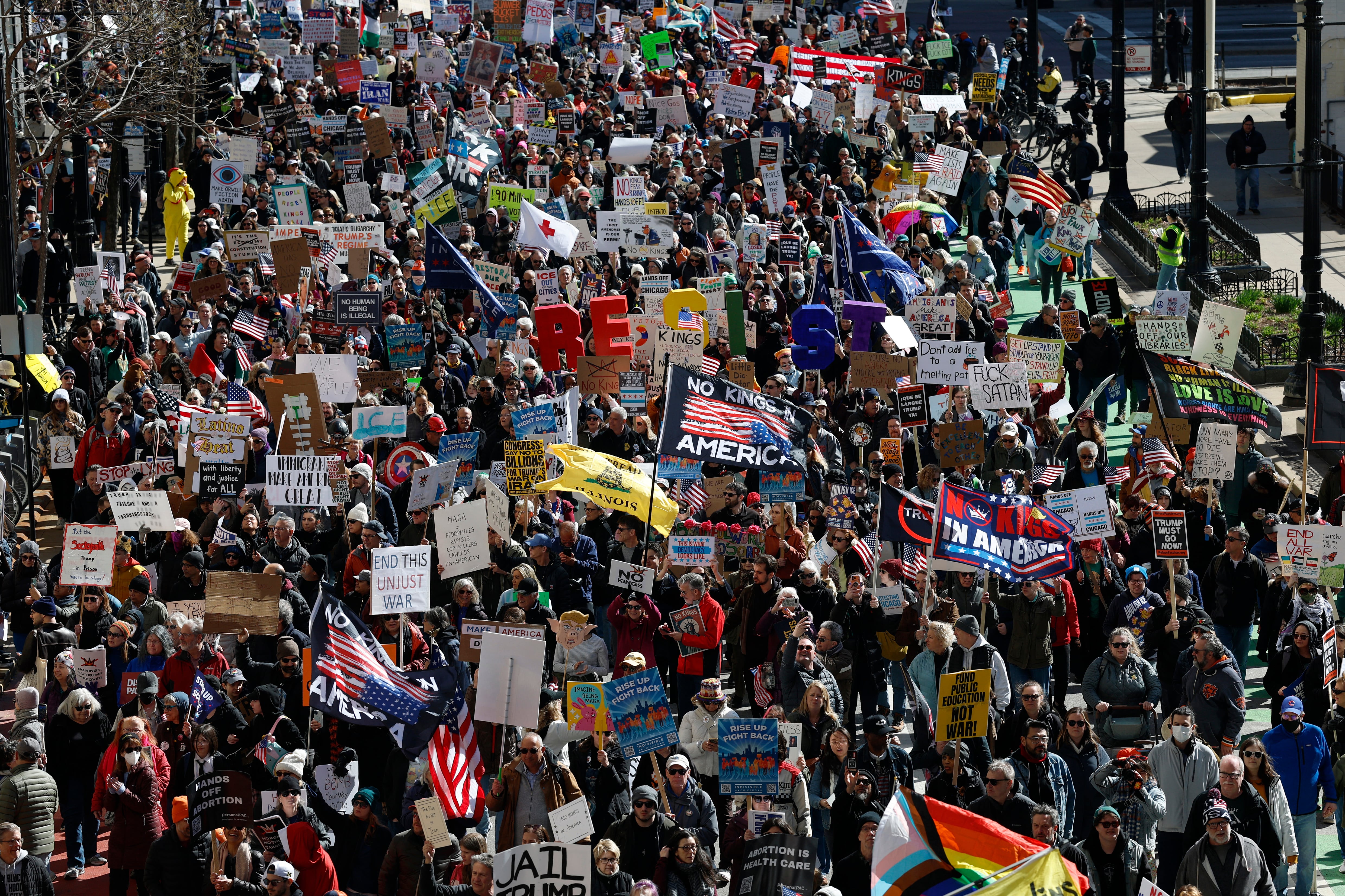 People hold signs and flags as they march during the "No Kings" national day of protest in Chicago on March 28, 2026. Nationwide protests against US President Donald Trump are expected Saturday as millions of people vent fury over what they see as his authoritarian bent and other forms of cruel, law-trampling governance. It is the third time in less than a year that Americans will take to the streets as part of a grassroots movement called "No Kings," the most vocal and visual conduit for opposition to Trump since he began his second term in January 2025. (Photo by KAMIL KRZACZYNSKI / AFP)