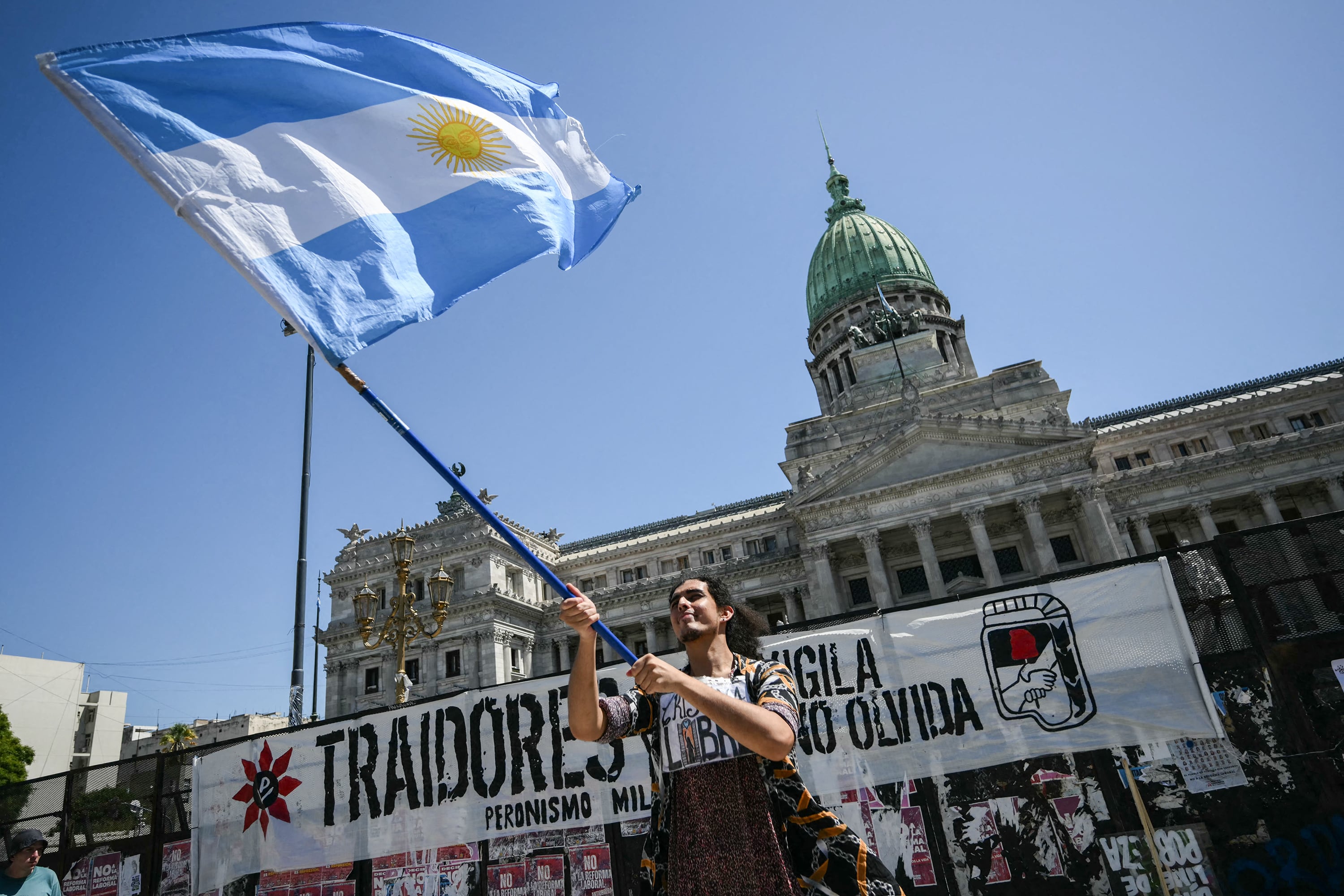 A demonstrator waves a national flag during a protest outside the Congress building, where Argentina's President Javier Milei's labour reforms