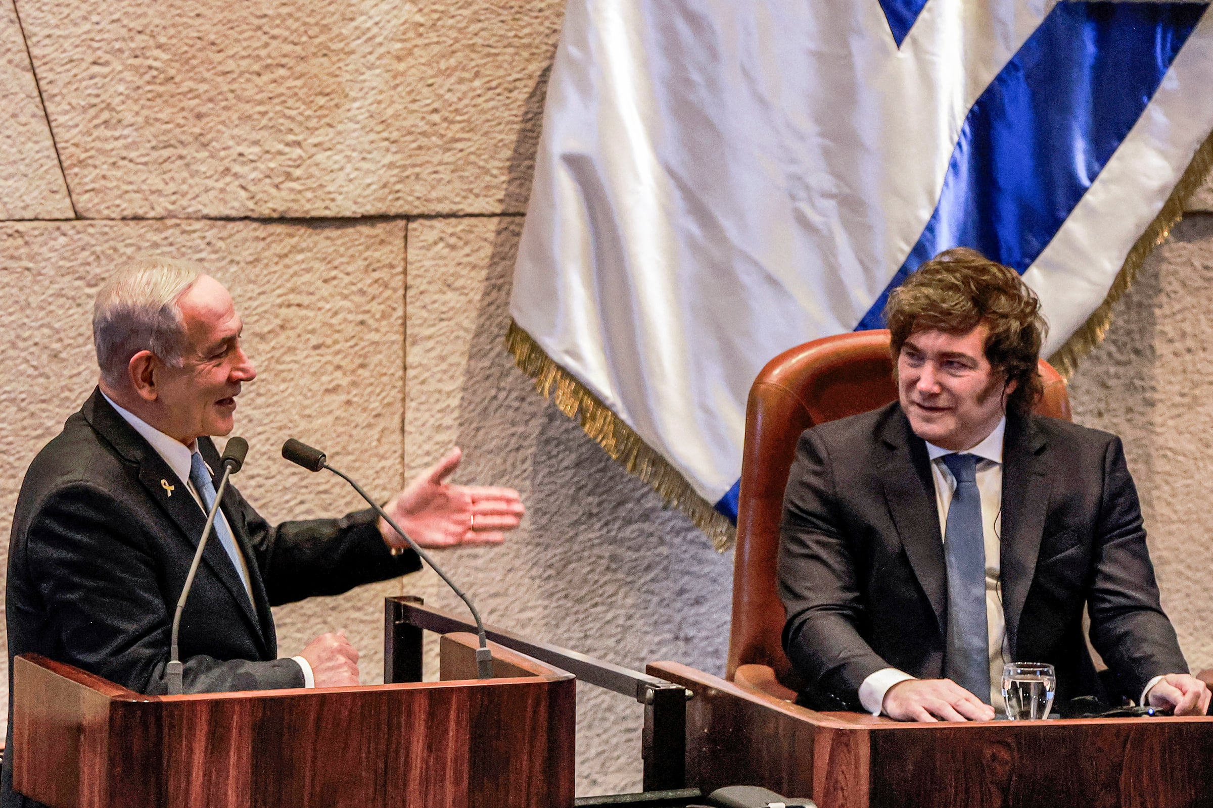 (L to R) Israel's Prime Minister Benjamin Netanyahu addresses Argentina's President Javier Milei as the latter attends a session of the Israeli parliament