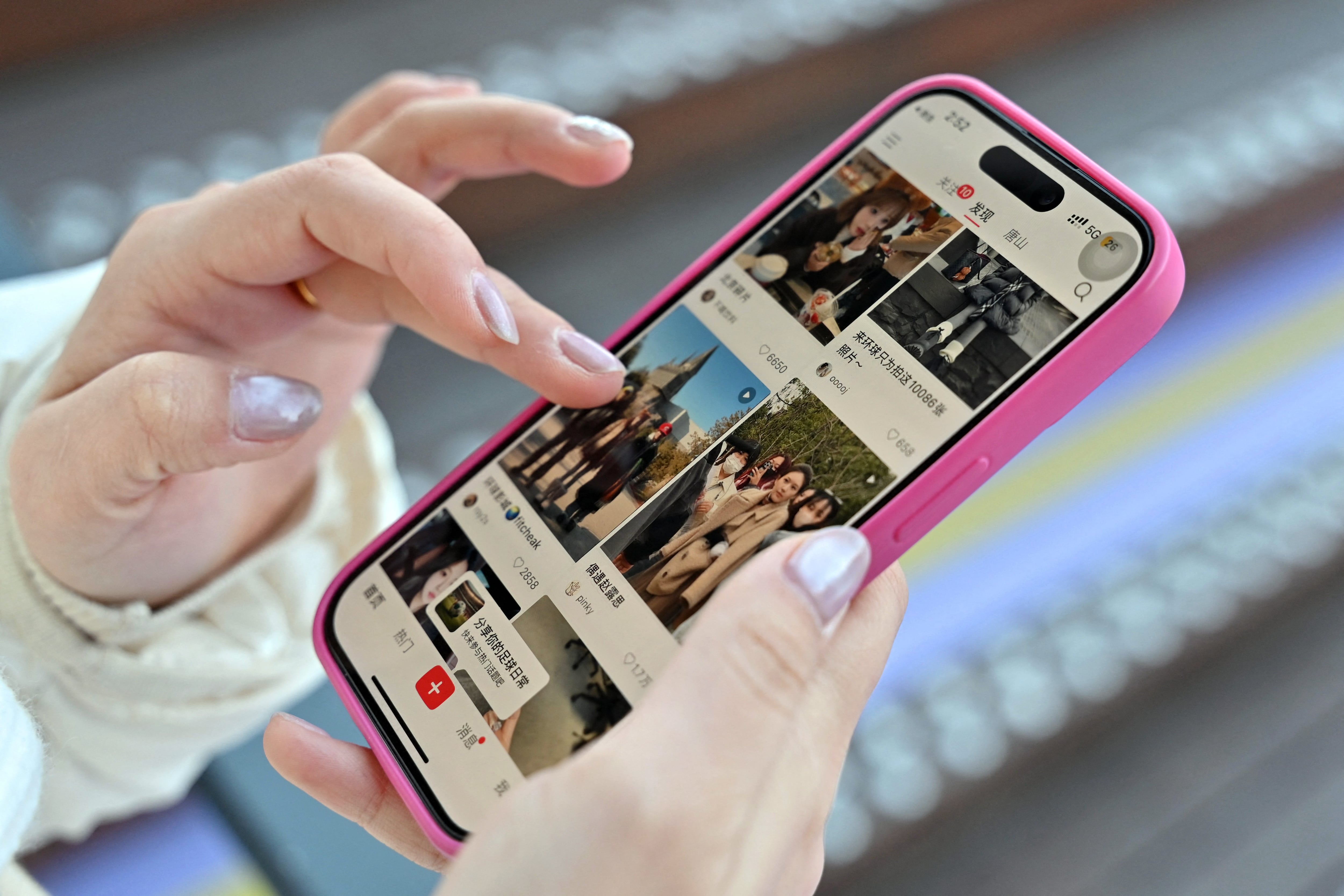 Una ilustración fotográfica muestra a una mujer sosteniendo su teléfono inteligente que muestra la aplicación china de redes sociales y comercio electrónico Xiaohongshu, también conocida como RedNote, en Beijing el 15 de enero de 2025.  (Foto de ADEK BERRY / AFP)