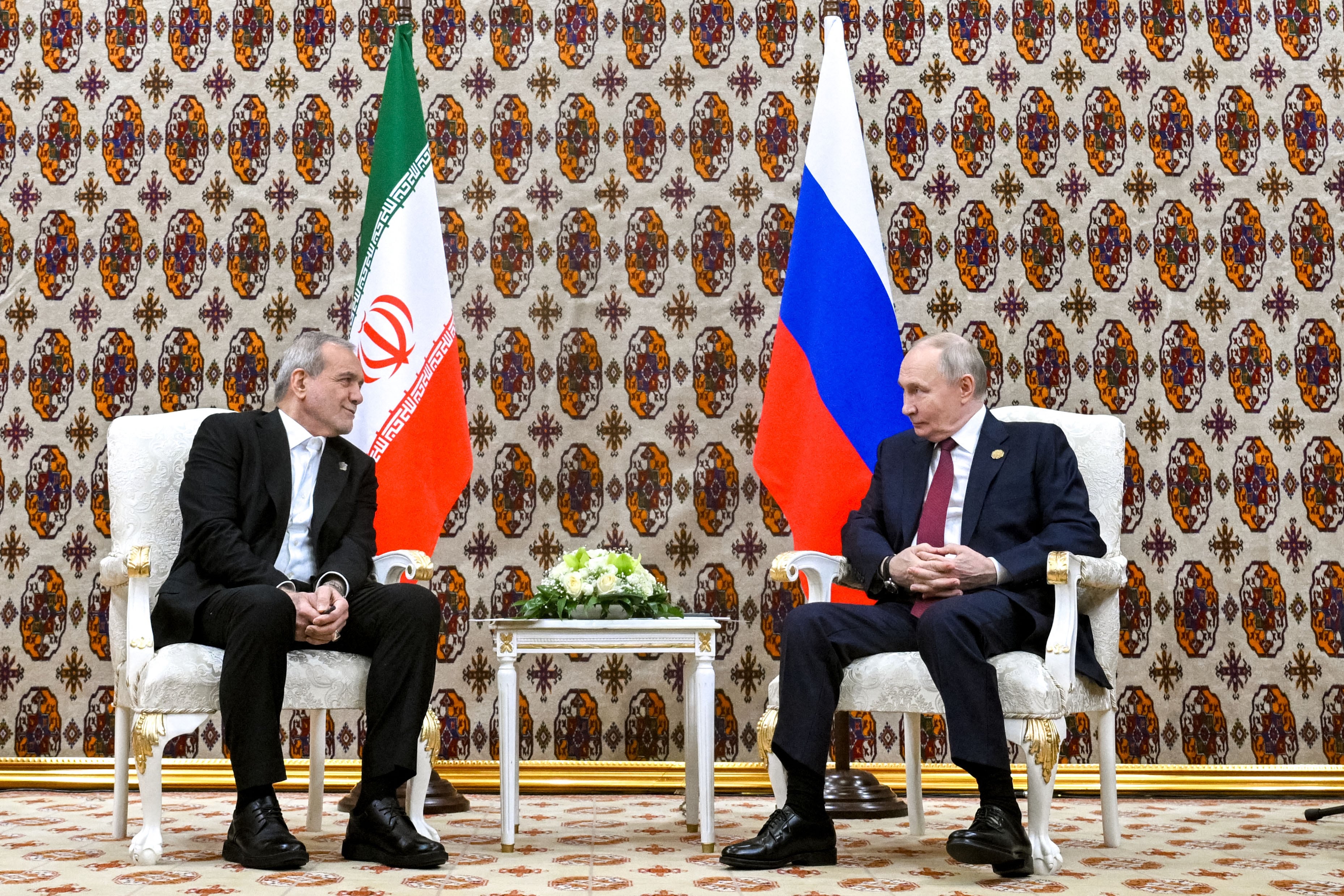 In this pool photograph distributed by the Russian state agency Sputnik, Russia's President Vladimir Putin and Iranian President Masoud Pezeshkian hold a meeting in Ashgabat on December 12, 2025. (Photo by Kristina Kormilitsyna / POOL / AFP)