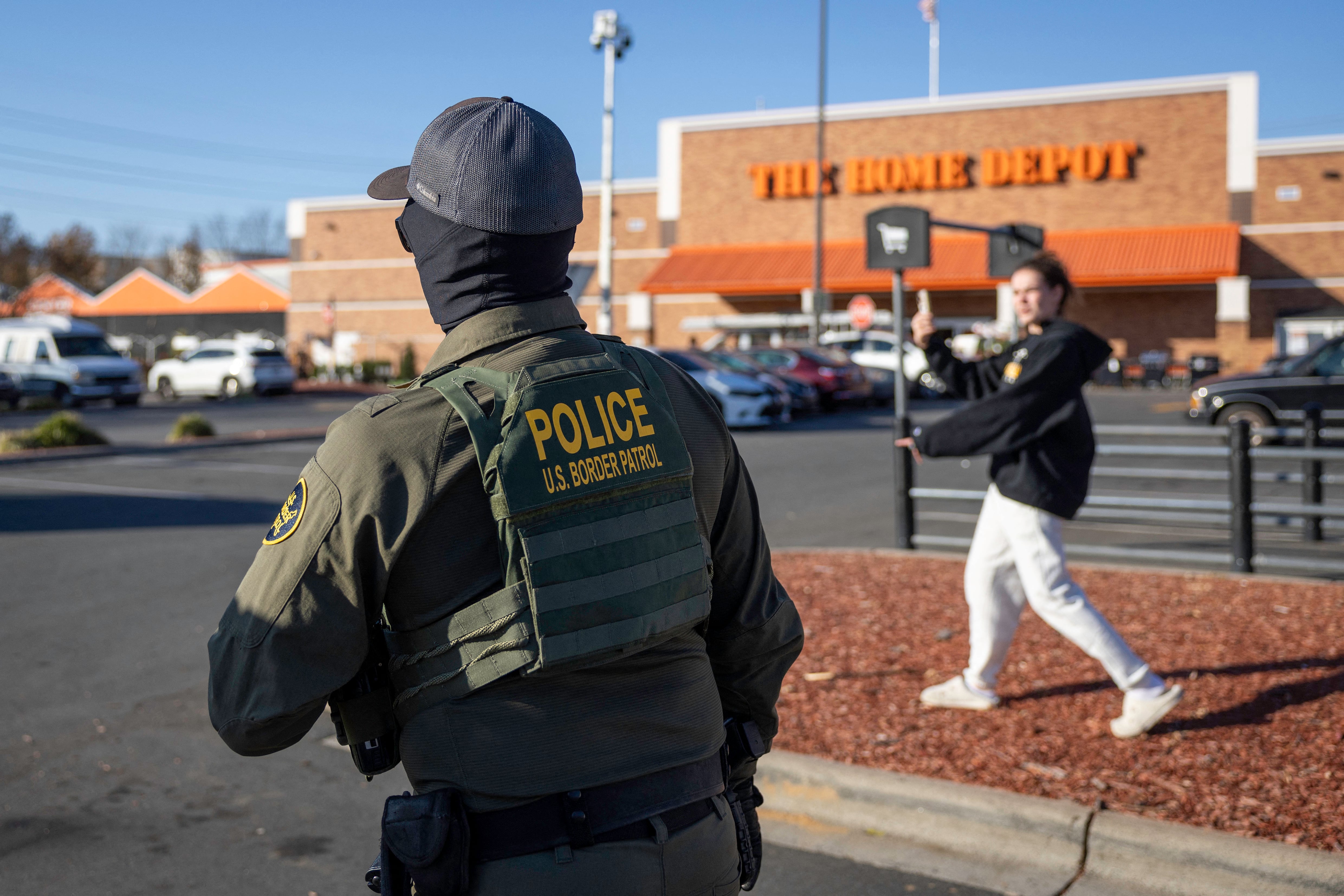 CHARLOTTE, NORTH CAROLINA - NOVEMBER 19: An activist records a U.S. Border Patrol agent outside a Home Depot store on November 19, 2025 in Charlotte, North Carolina. Federal agents continued searching for undocumented immigrants during Operation Charlotte's Web as they expanded their operations to other parts of North Carolina.   John Moore/Getty Images/AFP (Photo by JOHN MOORE / GETTY IMAGES NORTH AMERICA / Getty Images via AFP)
