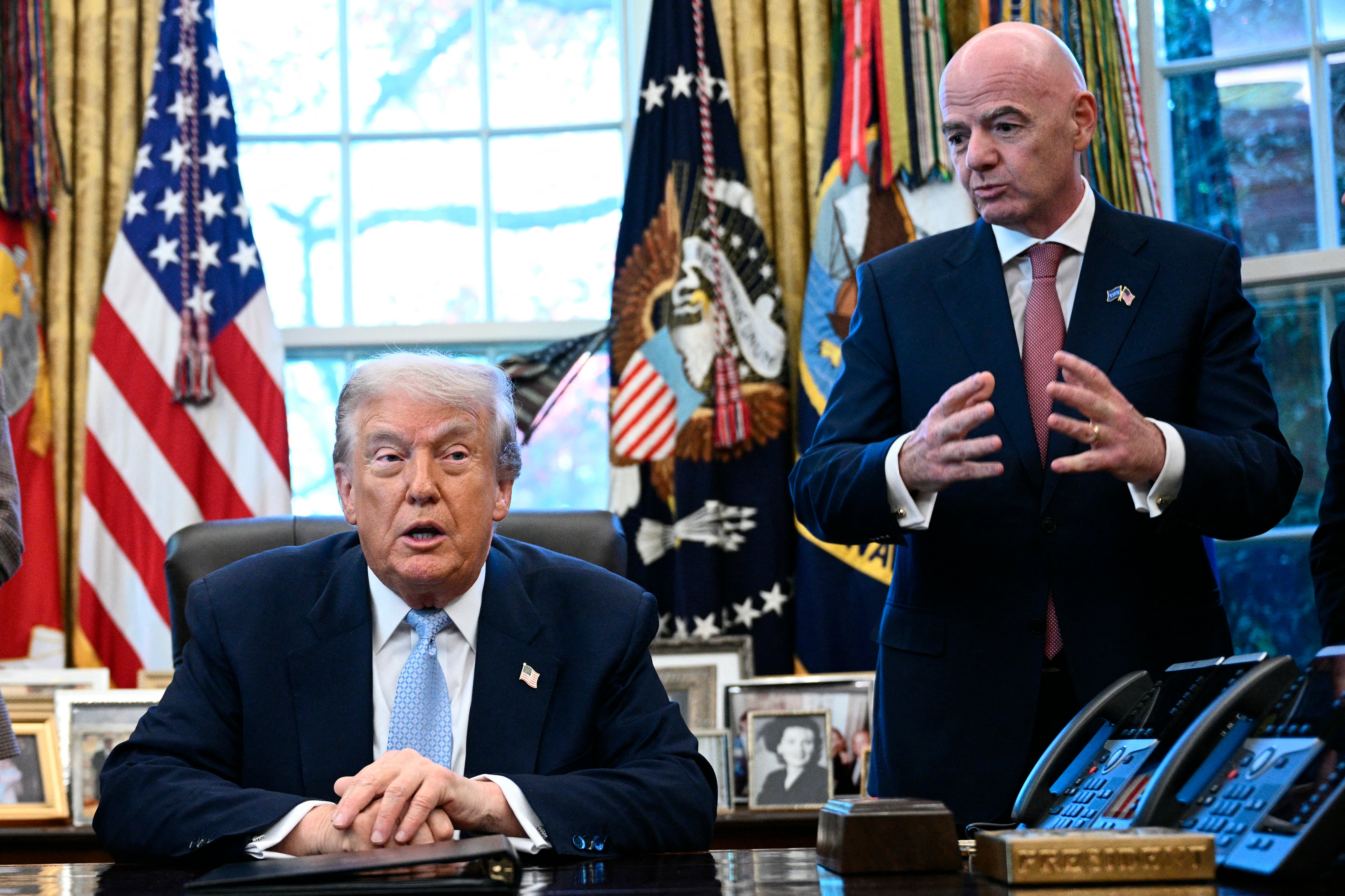 US President Donald Trump (C) spekas as FIFA president Gianni Infantino (R) and the US Secretary of Homeland Security Kristi Noem looks on during a meeting with the White House Task Force on the FIFA World Cup 2026 in the Oval Office of the White House in Washington, DC on November 17, 2025. (Photo by Brendan SMIALOWSKI / AFP)