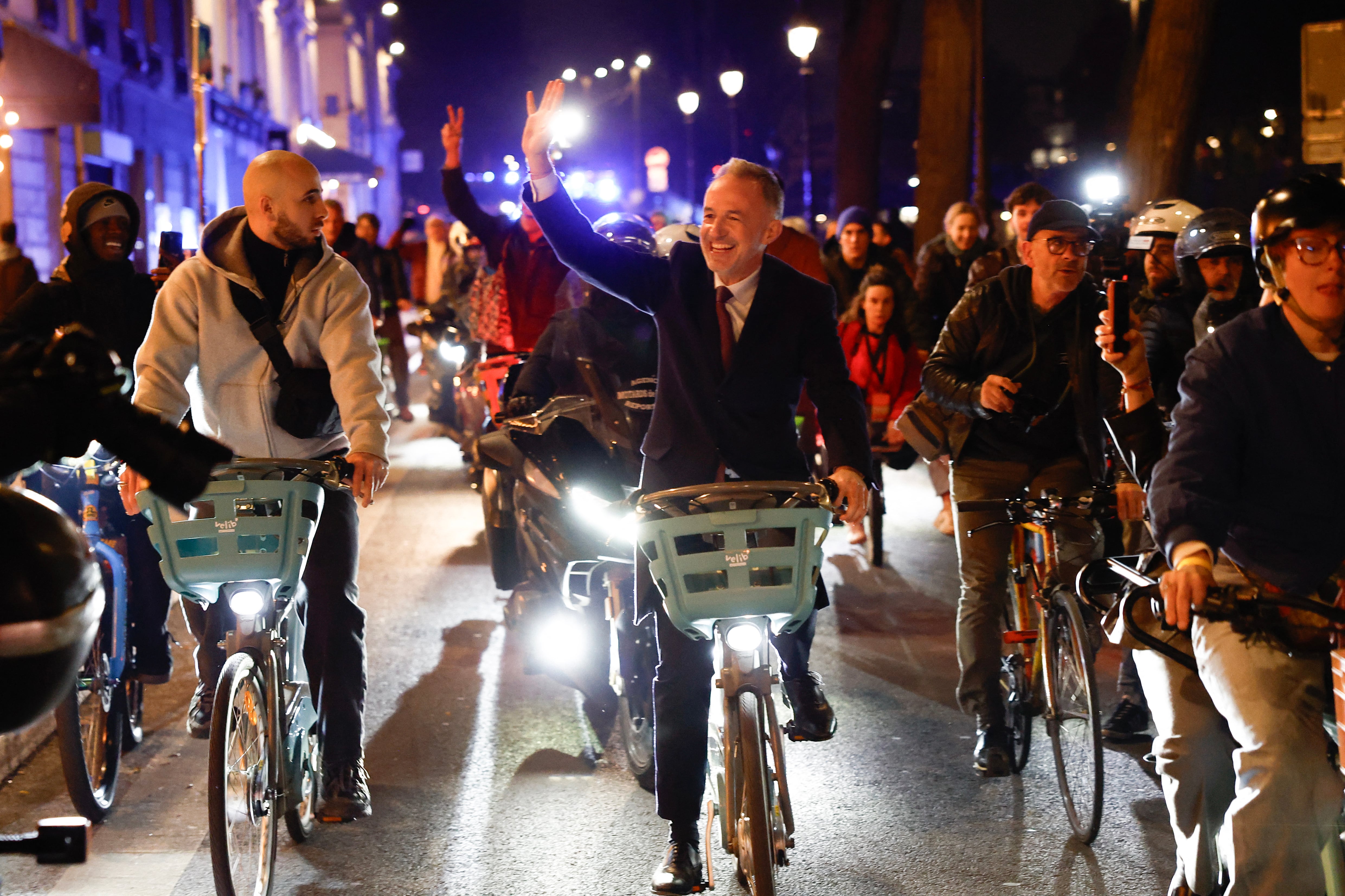 Socialistes et Apparentes' MP and Paris' Mayoral candidate Emmanuel Gregoire waves to supporters as he leaves ridding a Velib' public bike-sharing bicycle heading to Paris townhall after his victory following the announcement of official results of the second round of France's 2026 municipal elections in Paris on March 22, 2026. (Photo by Kenzo TRIBOUILLARD / AFP)
