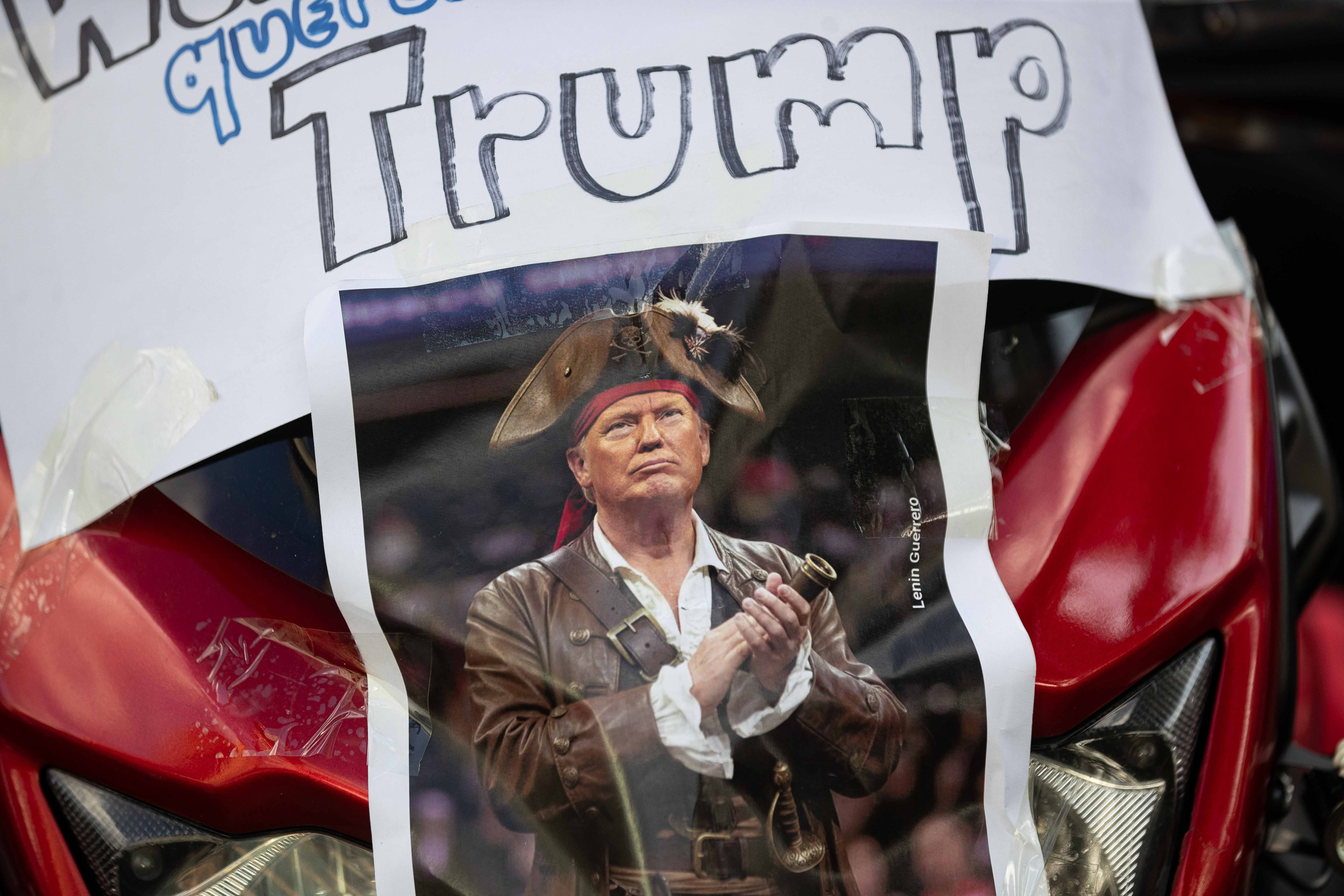 AME099. CARACAS (VENEZUELA), 22/12/2025.- Fotografía que muestra un cartel con la imagen del presidente de los Estados Unidos, Donald Trump, durante una caravana de motociclistas este lunes, en Caracas (Venezuela). Cientos de motoristas simpatizantes del chavismo, algunos disfrazados de piratas, recorrieron varias zonas de Caracas en protesta por la confiscación de dos buques con petróleo venezolano por parte de Estados Unidos y exhibieron afiches con la imagen del presidente Donald Trump con sombrero y parche. EFE/ Ronald Pena R