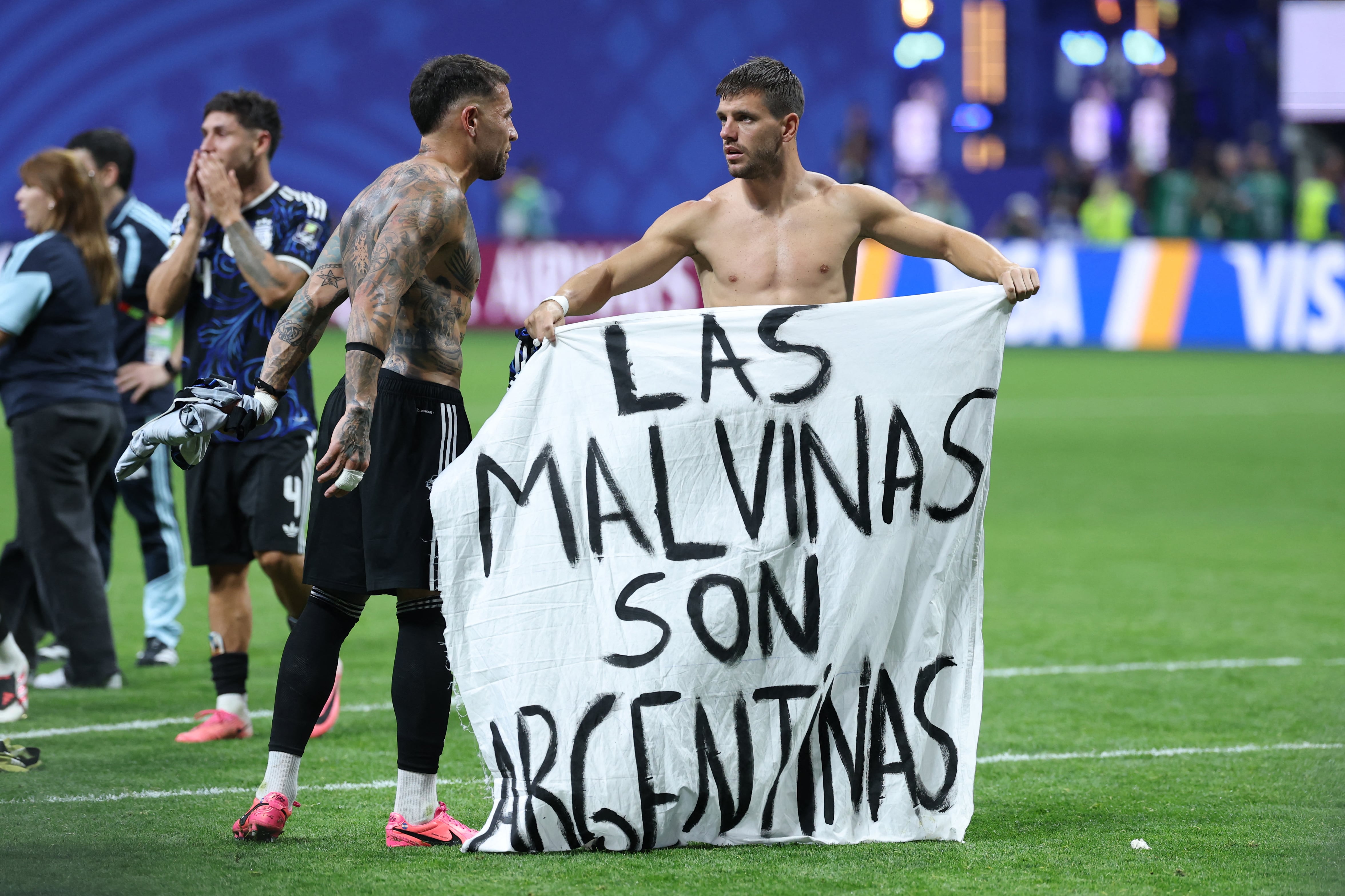 Argentina's defender #19 Nicolas Otamendi (L) and midfielder #11 Giovani Lo Celso show a banner that reads in Spanish, "The Malvinas (Falkland Islands) belong to Argentina," after winning the 2026 World Cup football tournament semi-final match between England and Argentina at the Atlanta Stadium in Atlanta on July 15, 2026.  (Photo by Thomas COEX / AFP)
