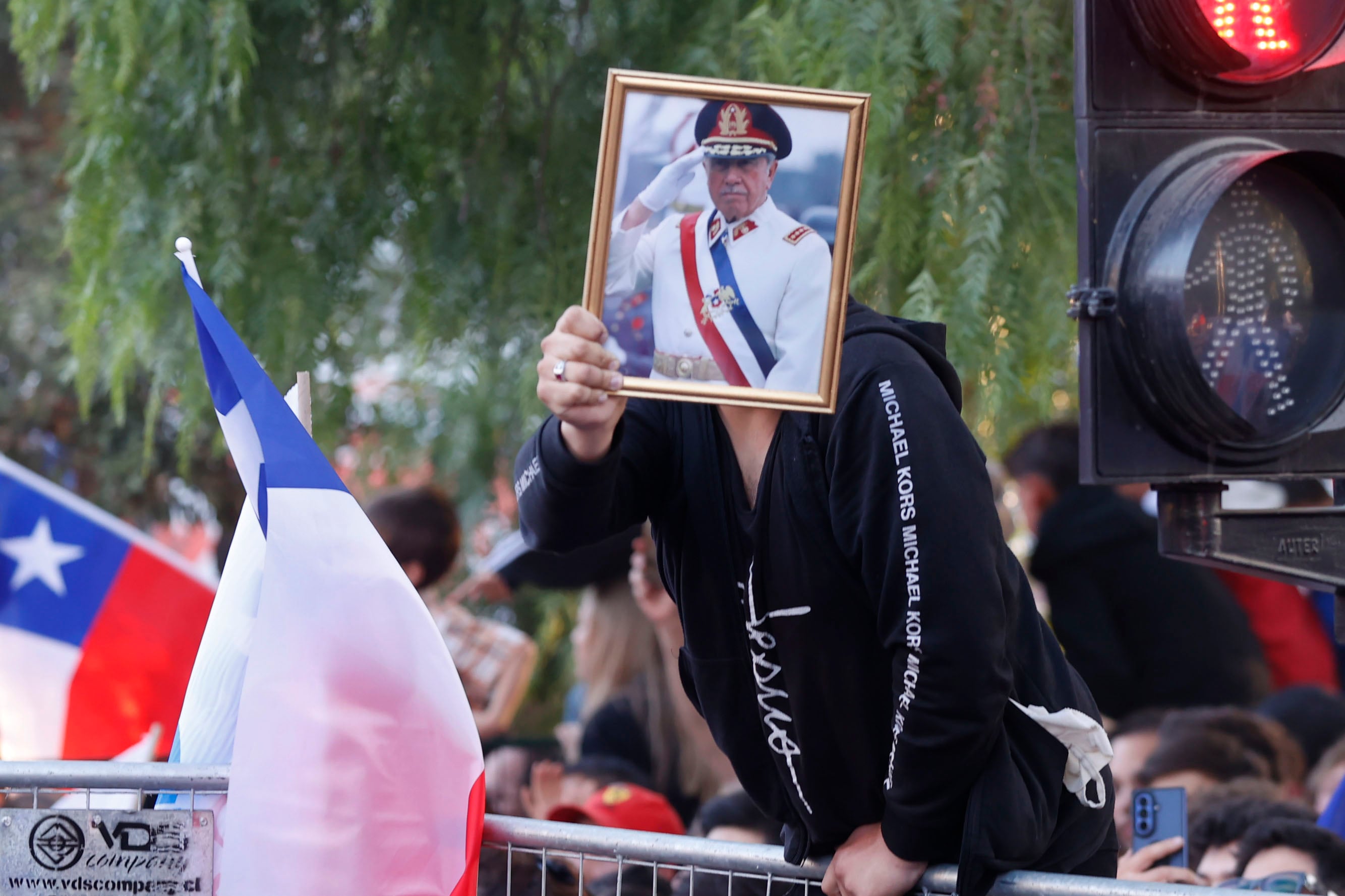 AME8323. SANTIAGO (CHILE), 14/12/2025.- Un simpatizante del candidato a la Presidencia de Chile por el Partido Republicano y el Partido Social Cristiano, José Antonio Kast, sostiene una fotografía de Augusto Pinochet, al conocer los primeros resultados de la segunda vuelta presidencial este domingo, en Santiago (Chile). El ultraderechista José Antonio Kast ganó este domingo las elecciones presidenciales de Chile, derrotando por un amplio margen a la izquierdista Jeannette Jara, con el 83,4 % de los votos escrutados. EFE/ Elvis González