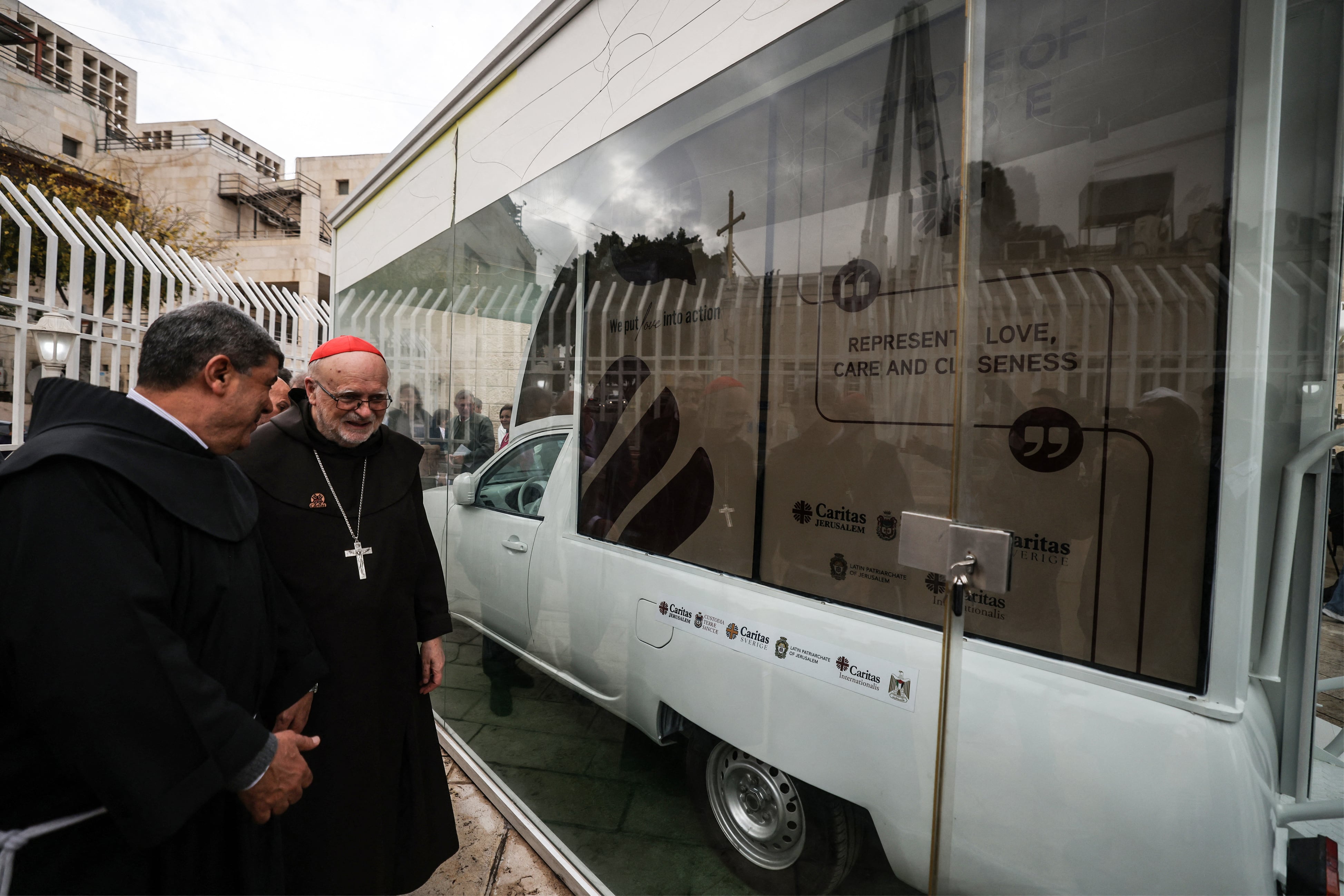 Father Ibrahim Faltas, from the Egyptian Catholic priest of the Franciscan Order (L) and Swedish Cardinal Anders Arborelius, the Bishop of Stockholm, inspect the "Vehicle of Hope", the Popemobile used by pope Francis during his 2014 visit to Bethlehem, which has been repurposed by the Catholic humanitarian organisation Caritas into a mobile children's clinic to be deployed in the Gaza Strip, in Bethlehem in the Israeli-occupied West Bank on November 25, 2025. The Gaza war was sparked by Hamas's October 7, 2023 attack on Israel, which resulted in the deaths of 1,221 people. Israel's retaliatory assault on Gaza has killed at over 69,500 Palestinians, according to figures from the health ministry that the UN considers reliable. (Photo by HAZEM BADER / AFP)