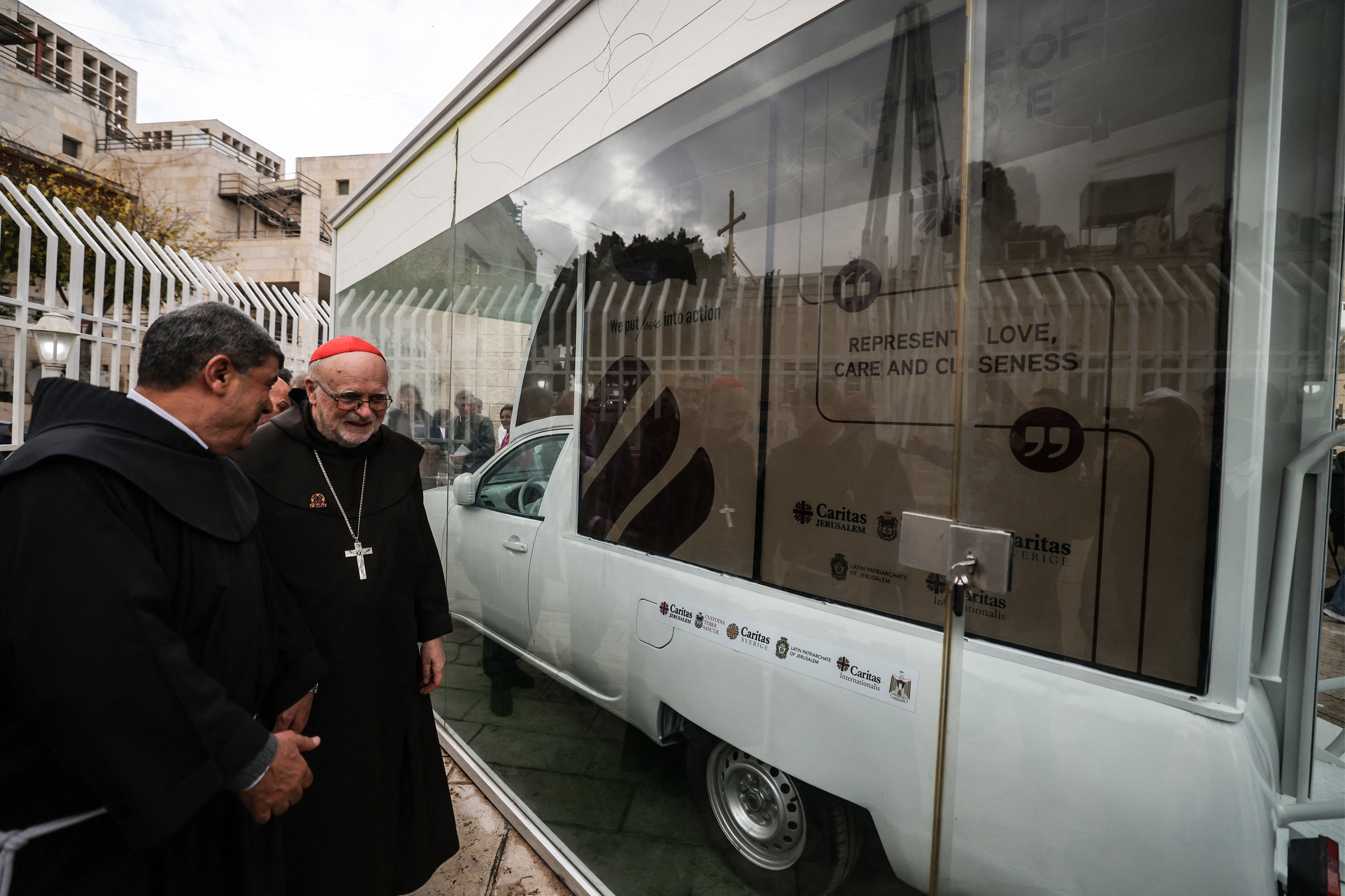 Father Ibrahim Faltas, from the Egyptian Catholic priest of the Franciscan Order (L) and Swedish Cardinal Anders Arborelius, the Bishop of Stockholm, inspect the "Vehicle of Hope", the Popemobile used by pope Francis during his 2014 visit to Bethlehem, which has been repurposed by the Catholic humanitarian organisation Caritas into a mobile children's clinic to be deployed in the Gaza Strip, in Bethlehem in the Israeli-occupied West Bank on November 25, 2025. The Gaza war was sparked by Hamas's October 7, 2023 attack on Israel, which resulted in the deaths of 1,221 people. Israel's retaliatory assault on Gaza has killed at over 69,500 Palestinians, according to figures from the health ministry that the UN considers reliable. (Photo by HAZEM BADER / AFP)
