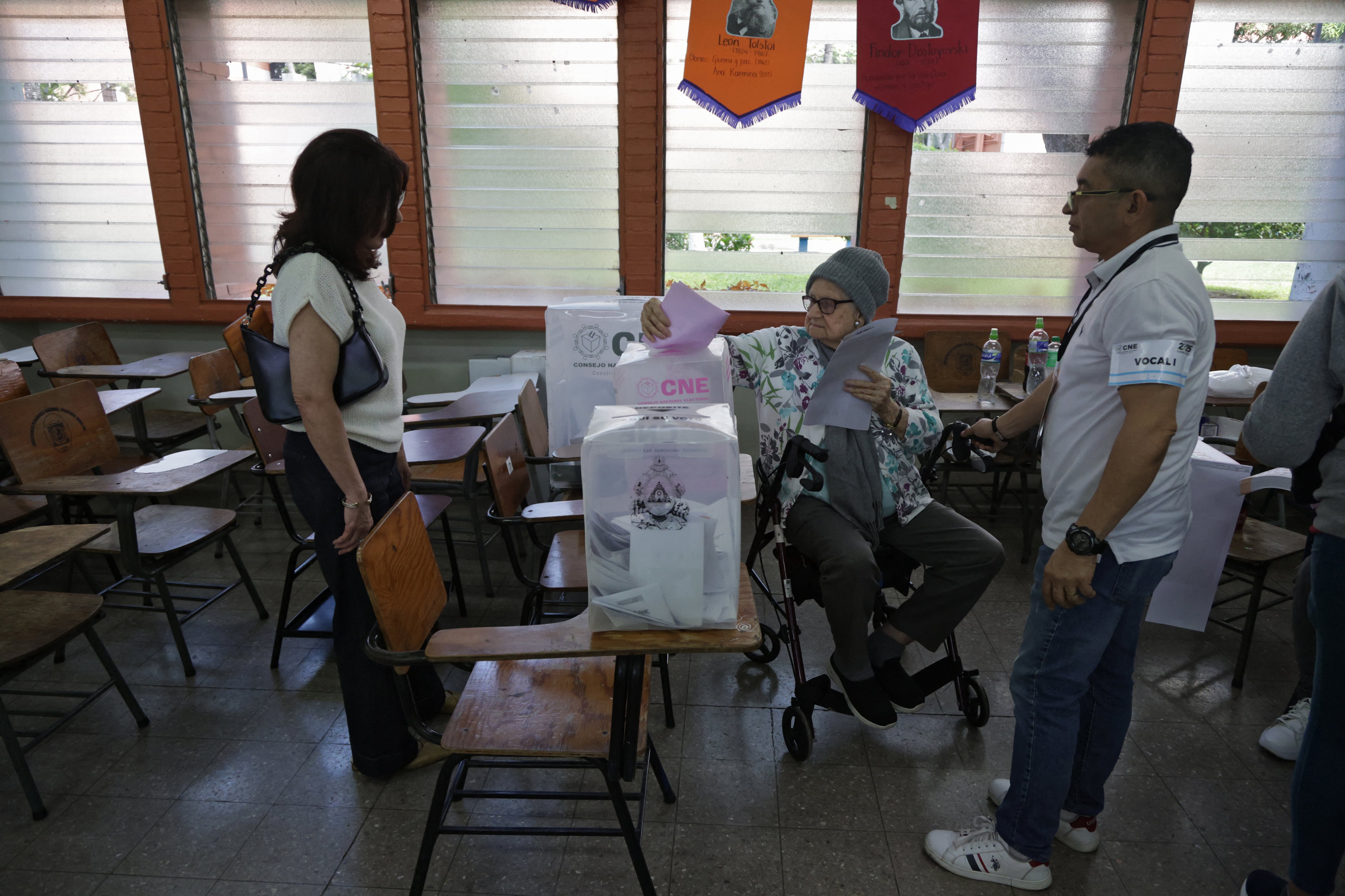 An elderly man is assisted as she casts her vote at a polling station during the general election in Tegucigalpa, on November 30, 2025. Hondurans voted for president on Sunday amid threats by US President Donald Trump to cut aid to the country if his preferred candidate loses. (Photo by Lucas AGUAYO / AFP)