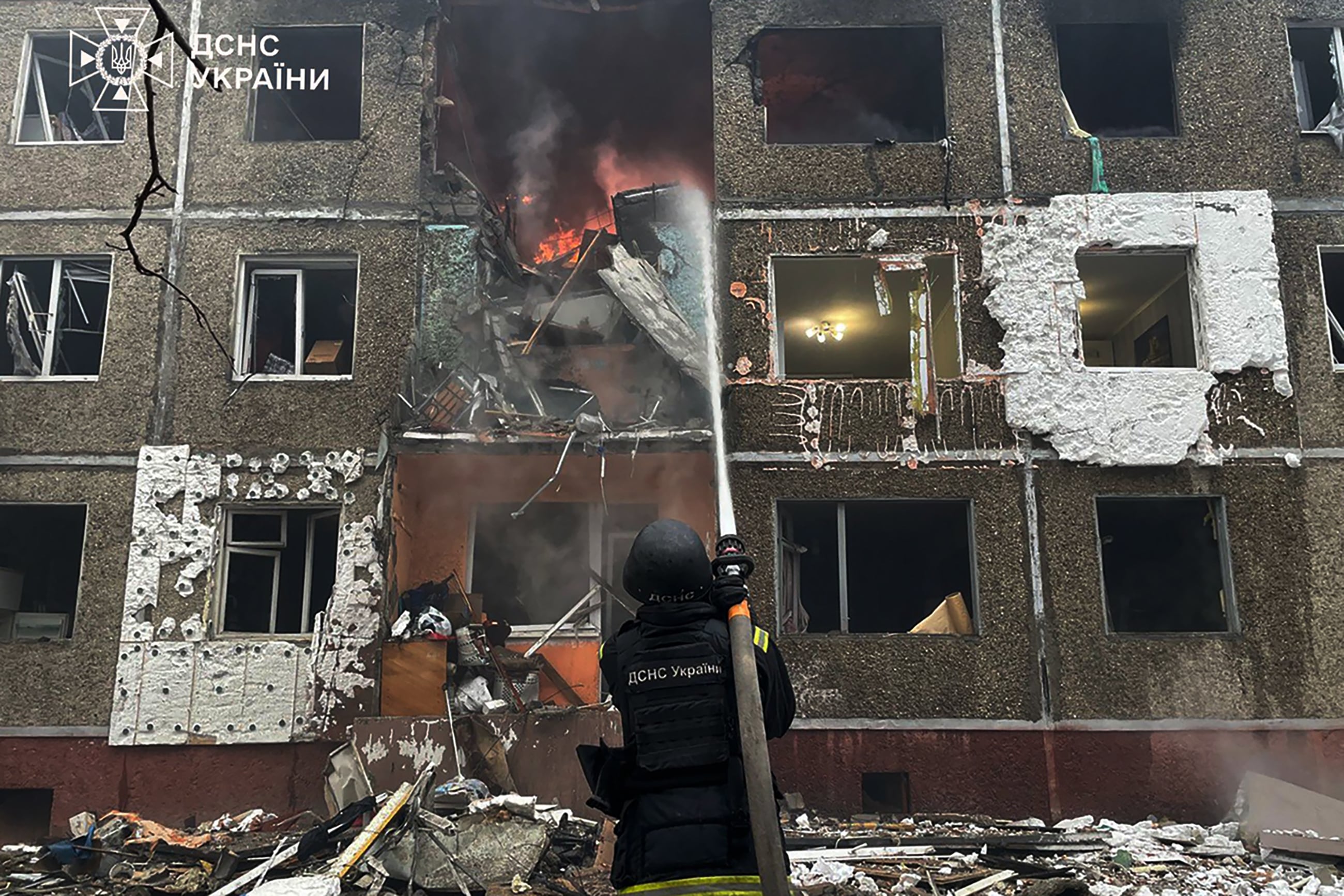 In this handout photograph taken and released by the Ukrainian Emergency Service on December 25, 2025, a Ukrainian rescuer extinguishes a fire at a damaged residential building following a drone strike in Chernihiv, amid the Russian invasion of Ukraine. (Photo by Handout / UKRAINIAN EMERGENCY SERVICE / AFP) / XGTY / RESTRICTED TO EDITORIAL USE - MANDATORY CREDIT "AFP PHOTO / UKRAINIAN EMERGENCY SERVICE" - NO MARKETING NO ADVERTISING CAMPAIGNS - DISTRIBUTED AS A SERVICE TO CLIENTS