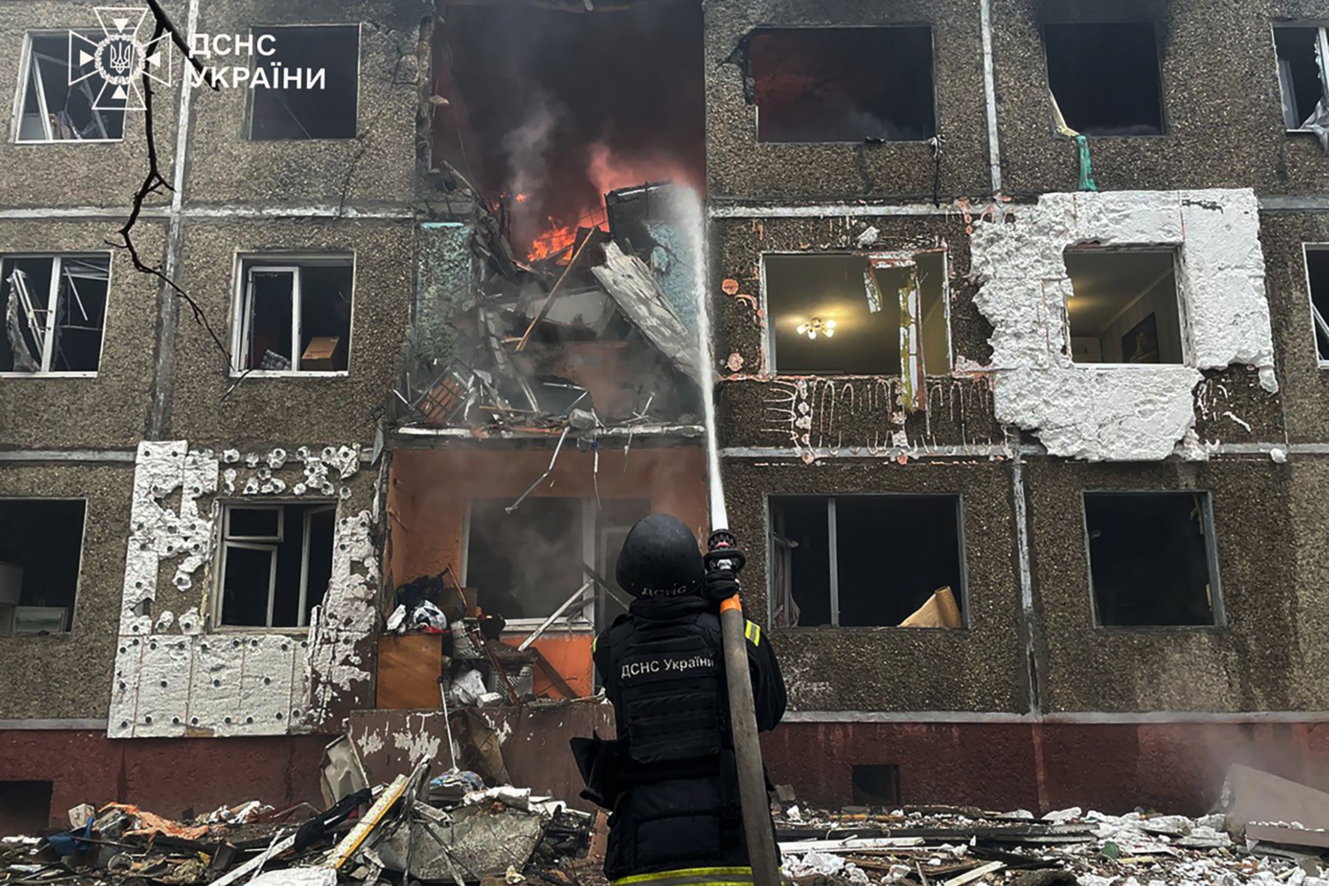 In this handout photograph taken and released by the Ukrainian Emergency Service on December 25, 2025, a Ukrainian rescuer extinguishes a fire at a damaged residential building following a drone strike in Chernihiv, amid the Russian invasion of Ukraine. (Photo by Handout / UKRAINIAN EMERGENCY SERVICE / AFP) / XGTY / RESTRICTED TO EDITORIAL USE - MANDATORY CREDIT "AFP PHOTO / UKRAINIAN EMERGENCY SERVICE" - NO MARKETING NO ADVERTISING CAMPAIGNS - DISTRIBUTED AS A SERVICE TO CLIENTS