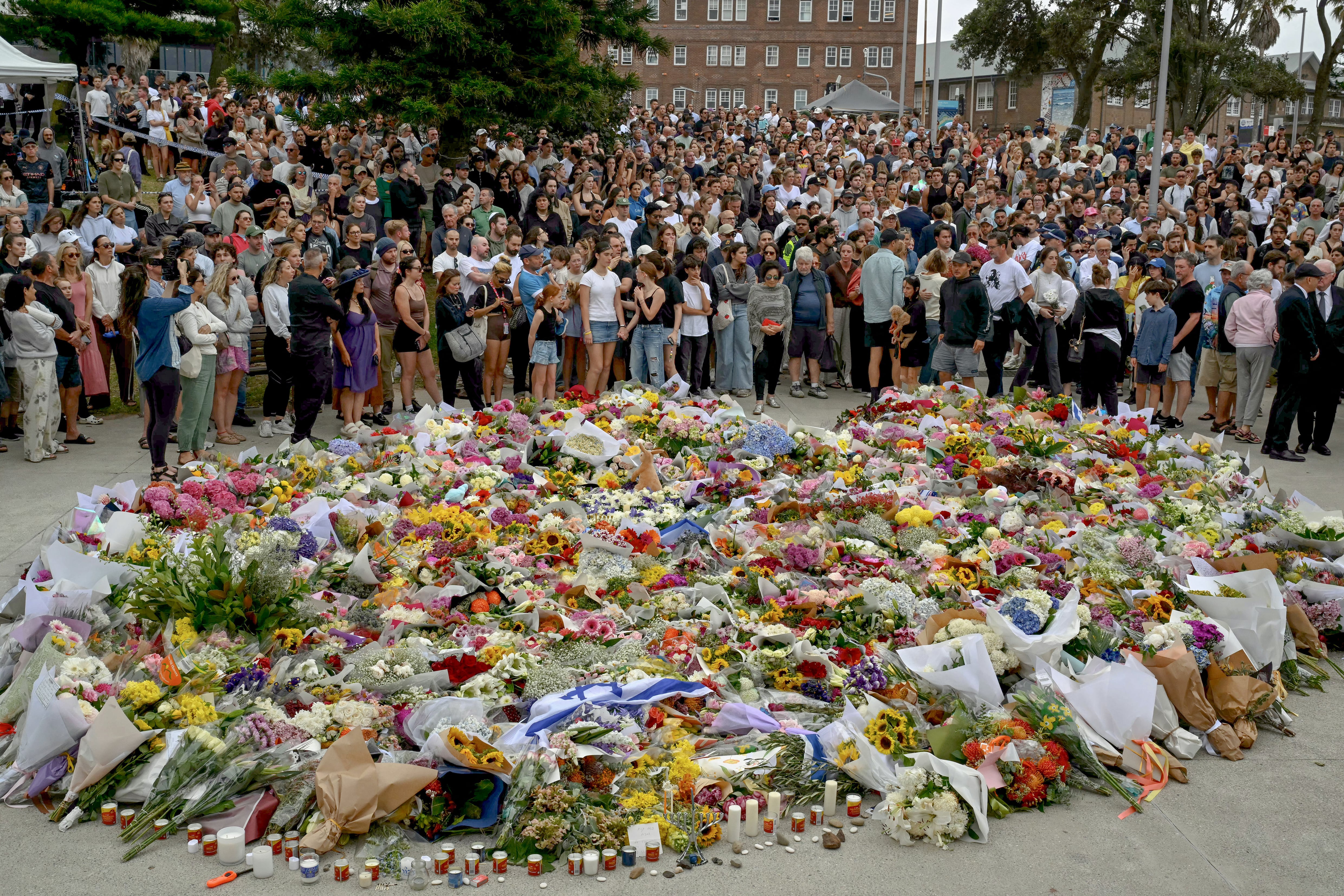 Mourners gather by floral tributes at the Bondi Pavillion in memory of the victims of a shooting at Bondi Beach, in Sydney on December 15, 2025. A father and son opened fire on a Jewish festival at Australia's Bondi Beach in a shooting spree that killed 15 people, including a child, authorities said on December 15, denouncing the attack as antisemitic "terrorism". (Photo by Saeed KHAN / AFP)