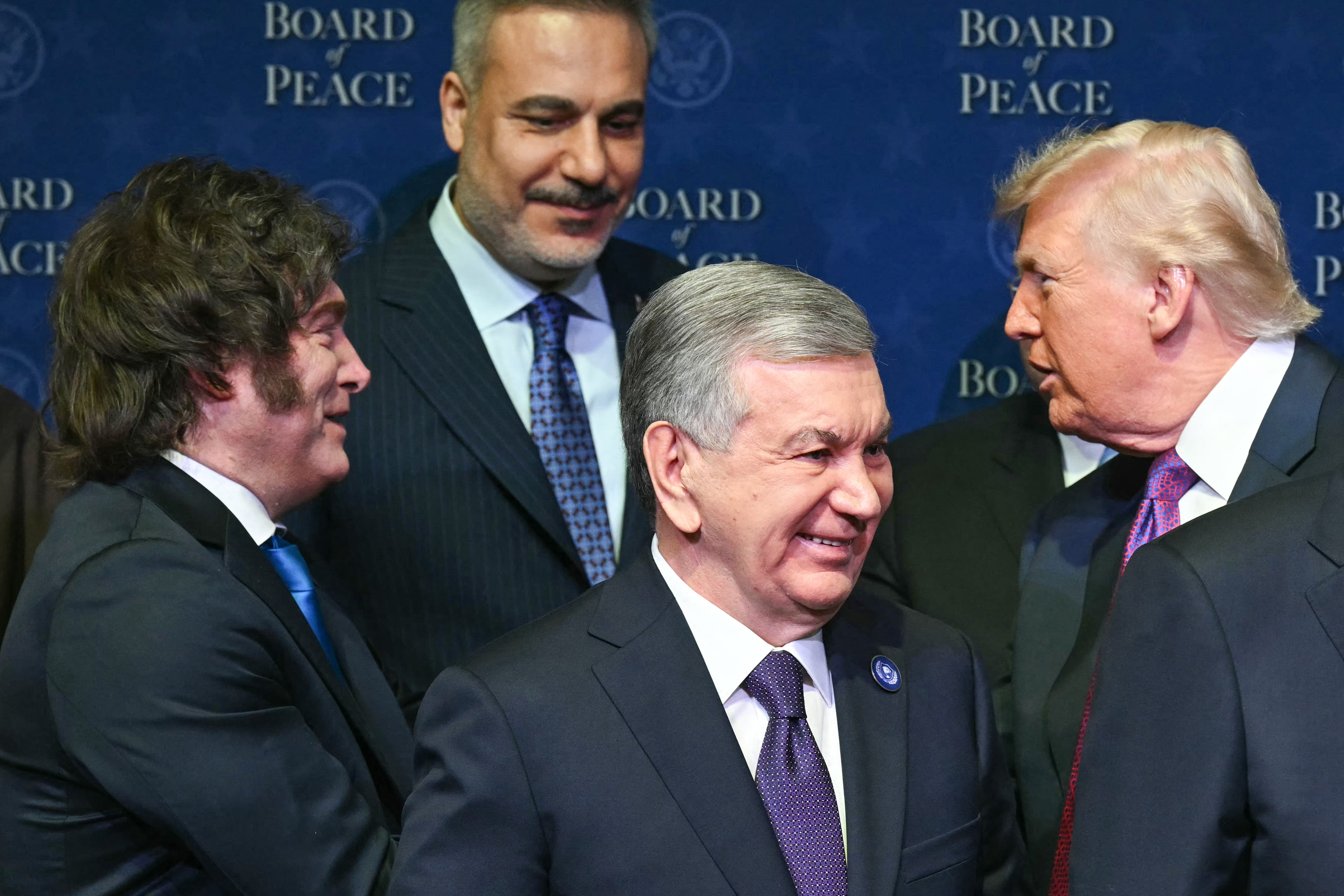 US President Donald Trump shakes hands with Argentina's President Javier Milei (2L) as leaders gather during a group photo during the inaugural meeting of the "Board of Peace"