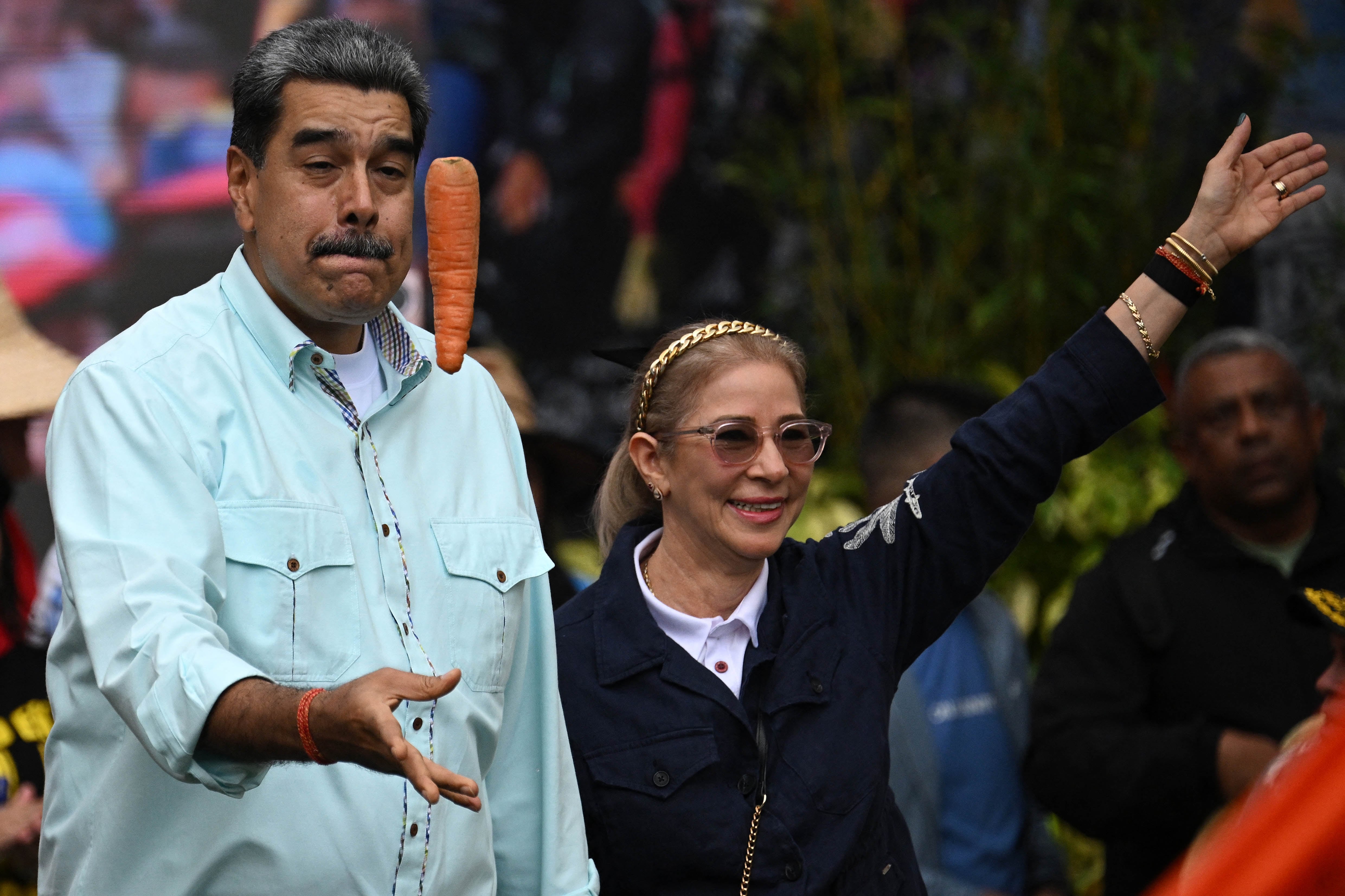 Venezuela's President Nicolas Maduro tosses a carrot into the air upon his arrival with First Lady Cilia Flores at a rally marking the anniversary of the Battle of Santa Ines, in Caracas on December 10, 2025. (Photo by Federico PARRA / AFP)
