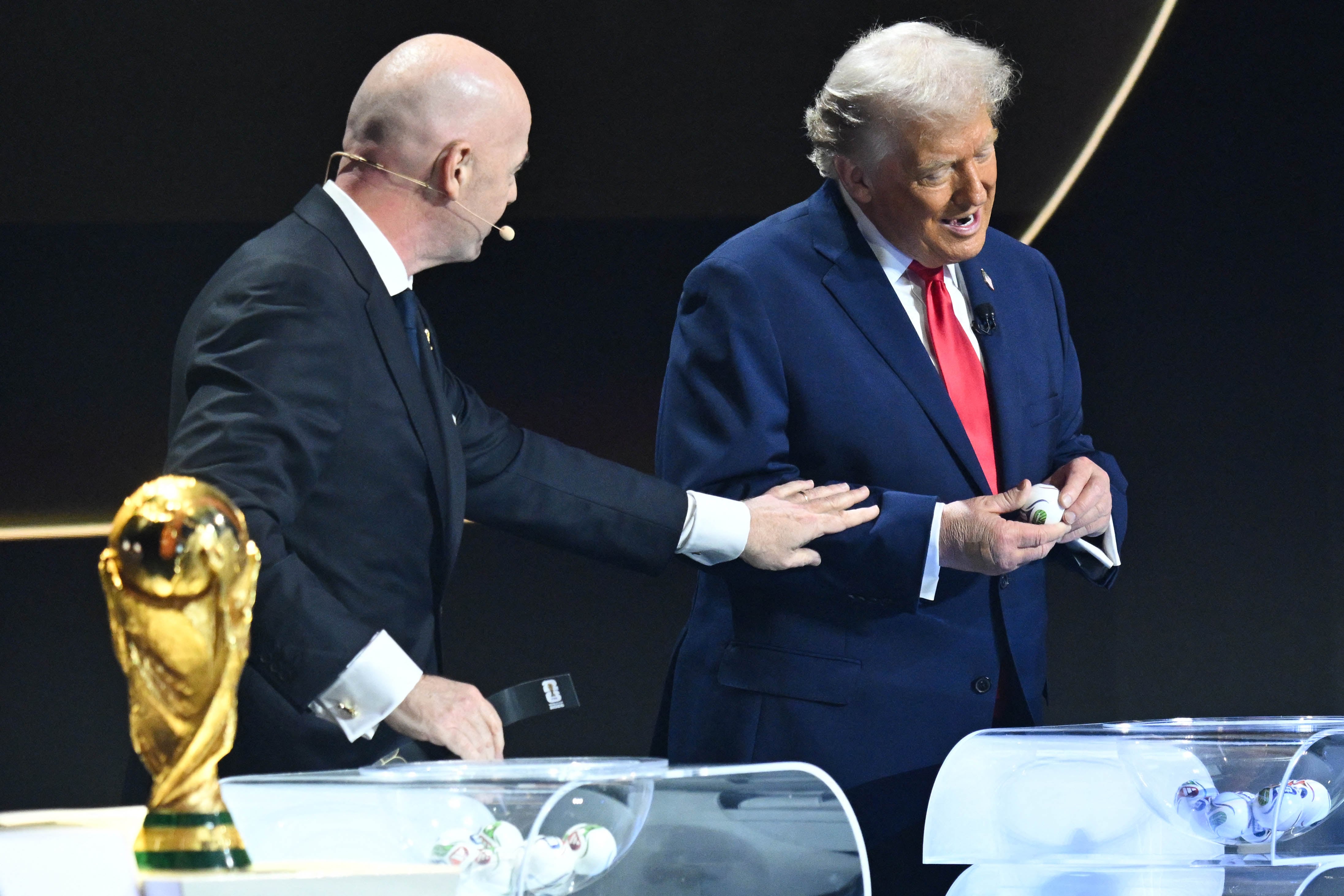 US President Donald Trump picks up a card next to Italian Fifa President Gianni Infantino during the draw for the 2026 FIFA Football World Cup taking place in the US, Canada and Mexico, at the Kennedy Center, in Washington, DC, on December 5, 2025. (Photo by SAUL LOEB / AFP)